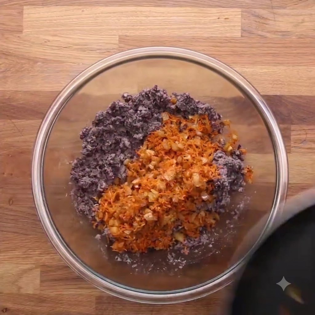 Avena instantánea vertida en un tazón de vidrio con frijoles negros triturados y zanahorias ralladas.