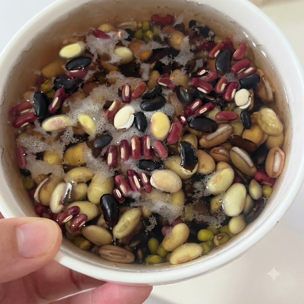 Frijoles mixtos remojados reposando en un tazón blanco con agua antes de ser colados.