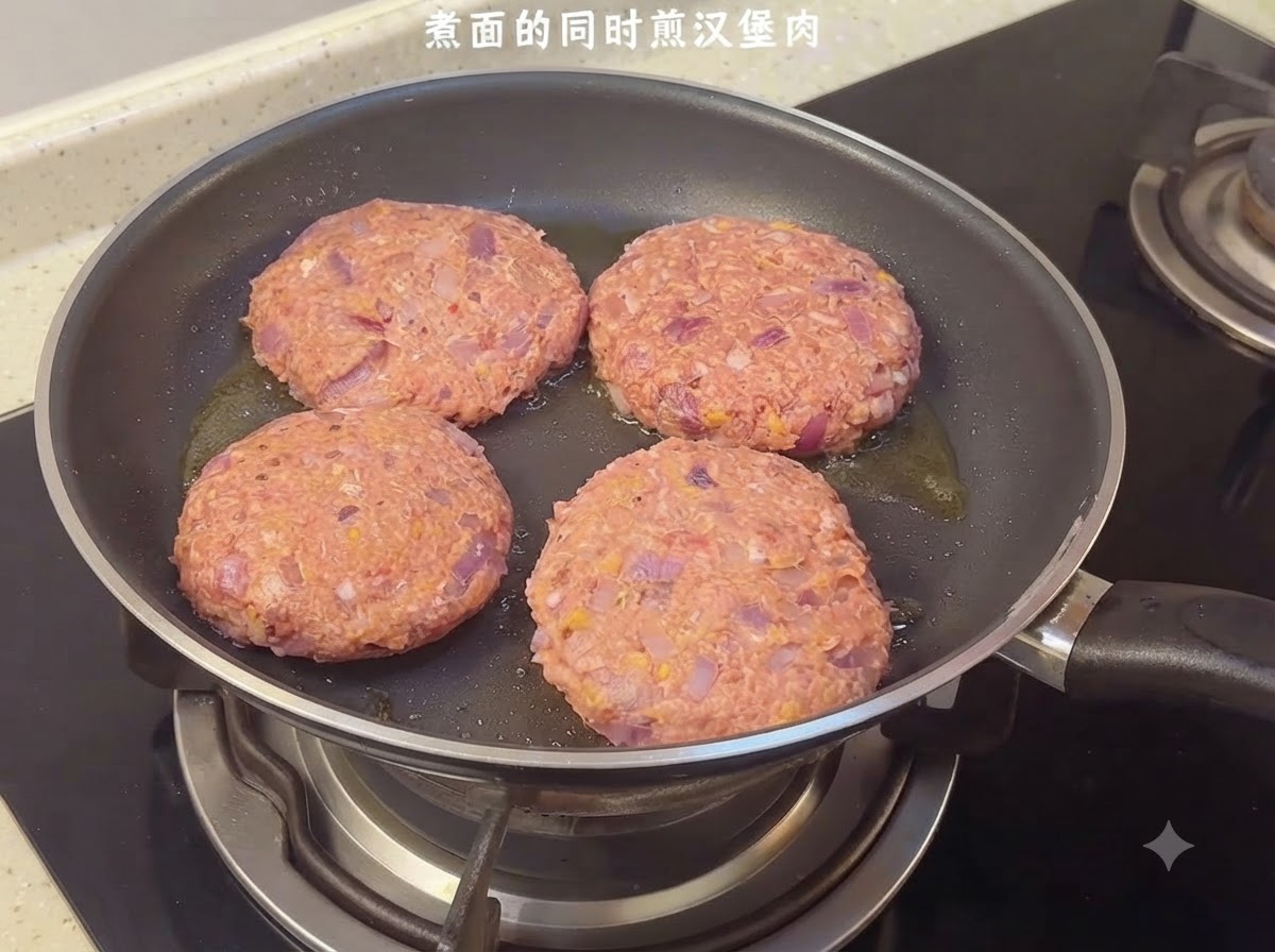 Cuatro hamburguesas de carne crudas chisporroteando en una sartén en la estufa.