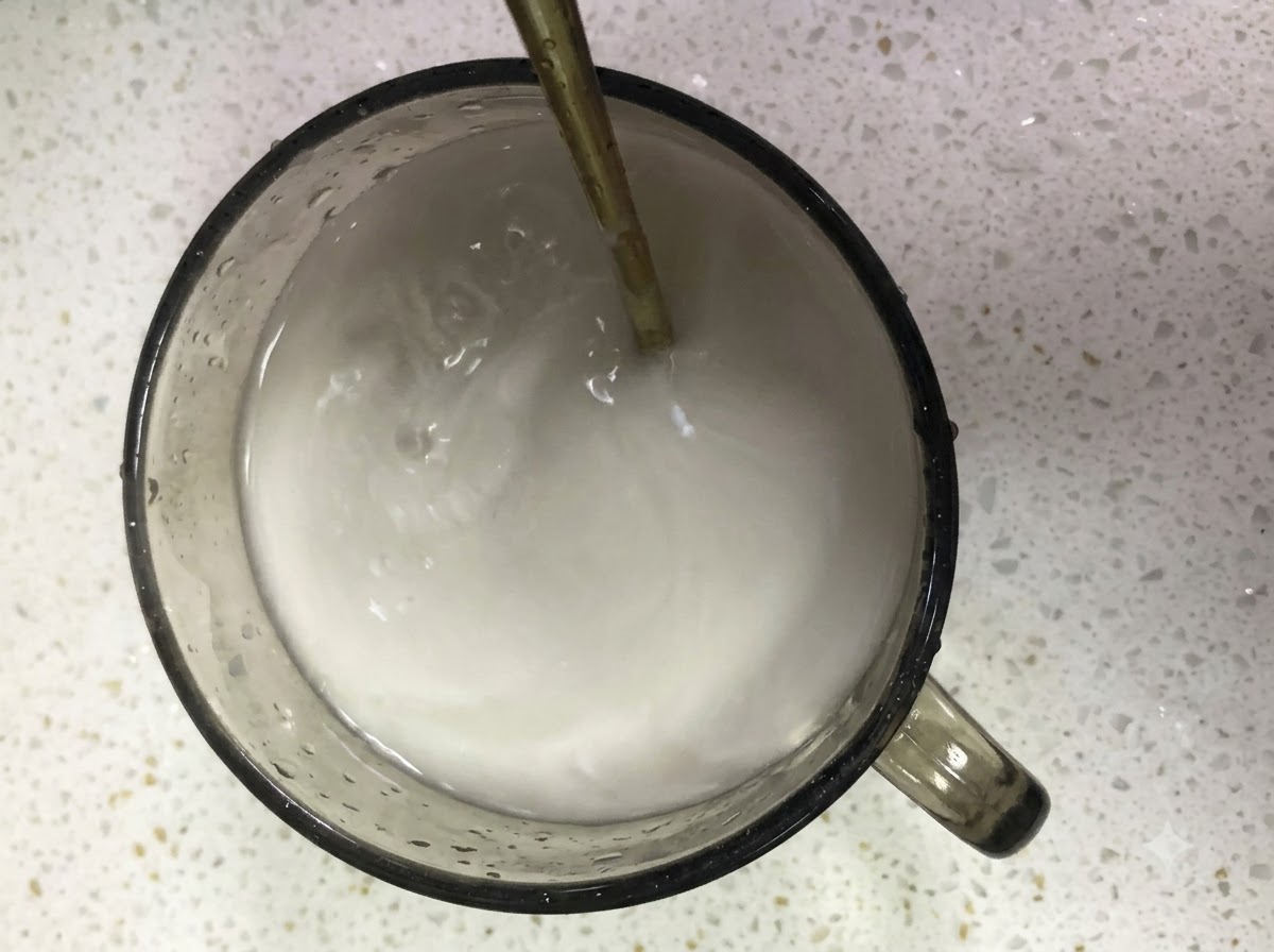 Almidón de boniato y agua mezclándose en un vaso de cristal con una cuchara.