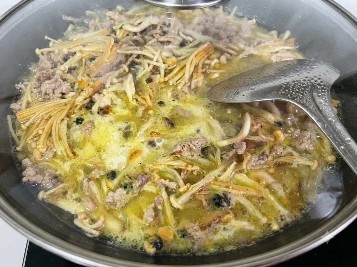 Líquido de almidón de boniato siendo vertido desde una taza medidora de cristal hacia el wok.