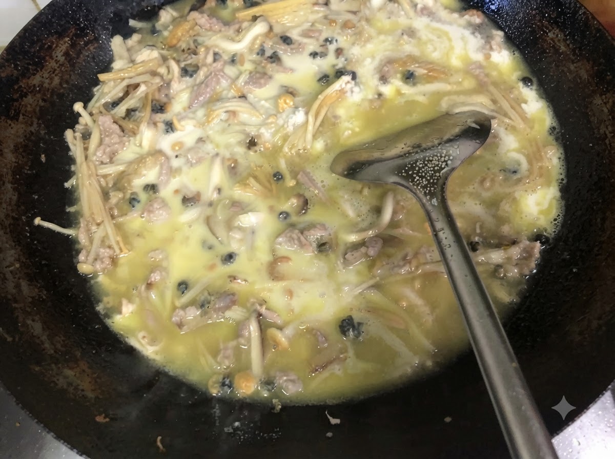 Cebollino verde picado fresco siendo mezclado en el relleno espeso cocinado dentro de un wok usando una espátula de metal.