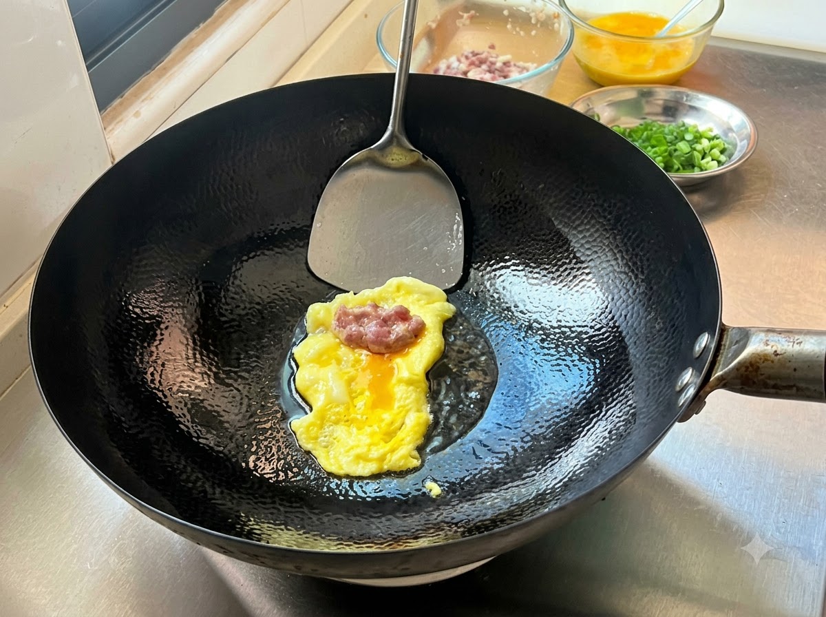 Una porción de carne picada sazonada reposando sobre una crepe de huevo delgada recién cocida en un wok caliente, lista para ser doblada.