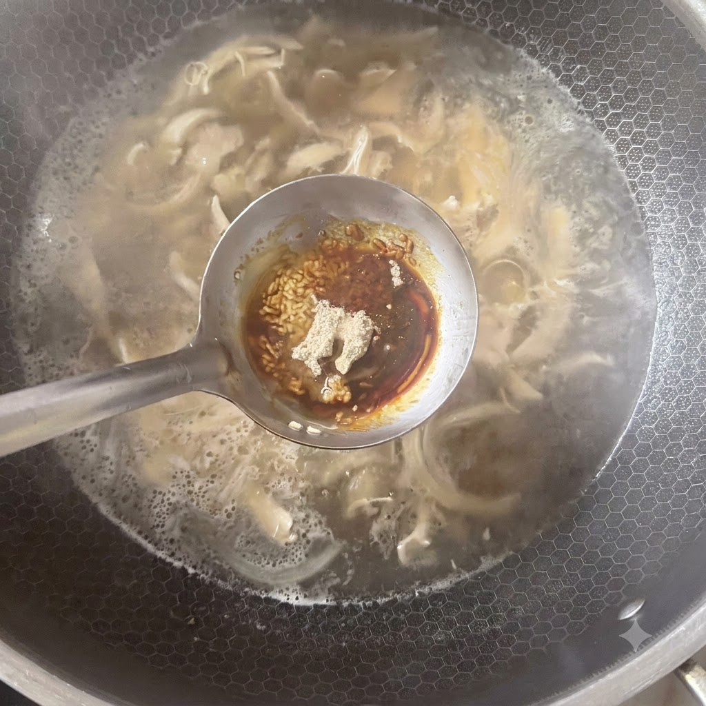 Un cucharón que sostiene varios condimentos, incluyendo pimienta blanca en polvo y salsas, posicionado sobre una olla de sopa a fuego lento.