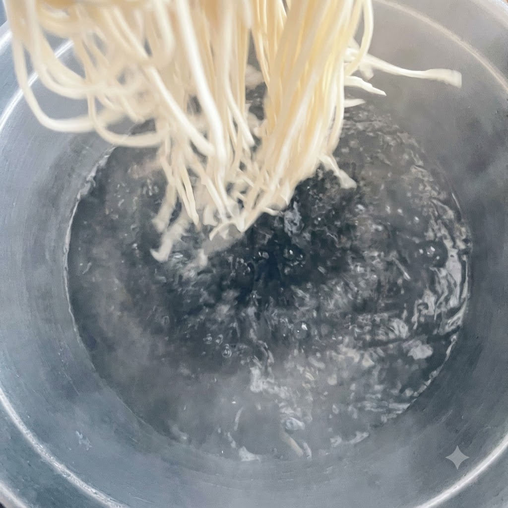 Fideos siendo añadidos a una olla grande con agua hirviendo.
