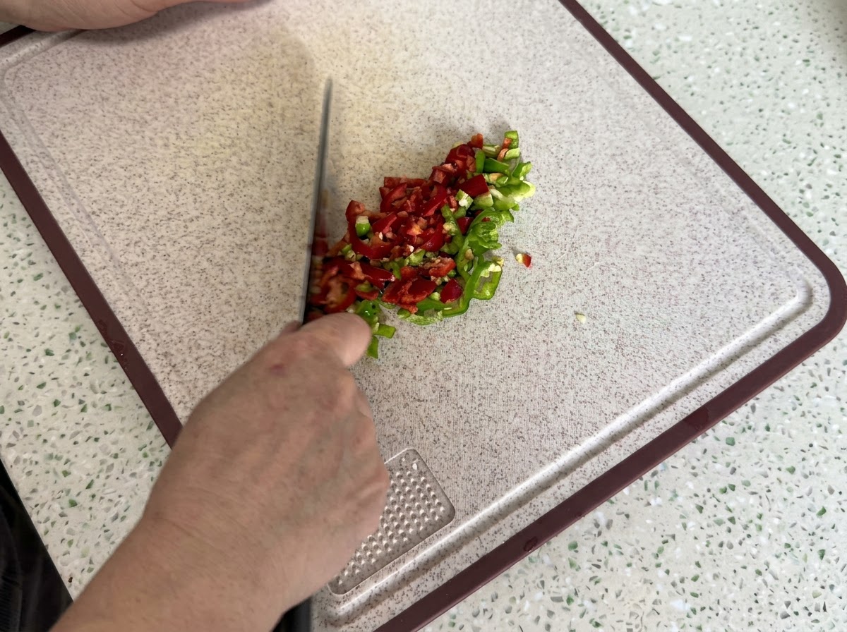 Chiles rojos y verdes finamente picados y cortados en cubitos en una tabla de cortar limpia.