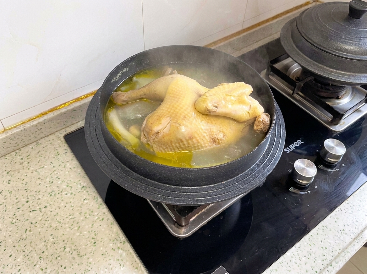 Un pollo entero cocido hirviendo a fuego lento dentro de una olla antes de ser porcionado en piezas.