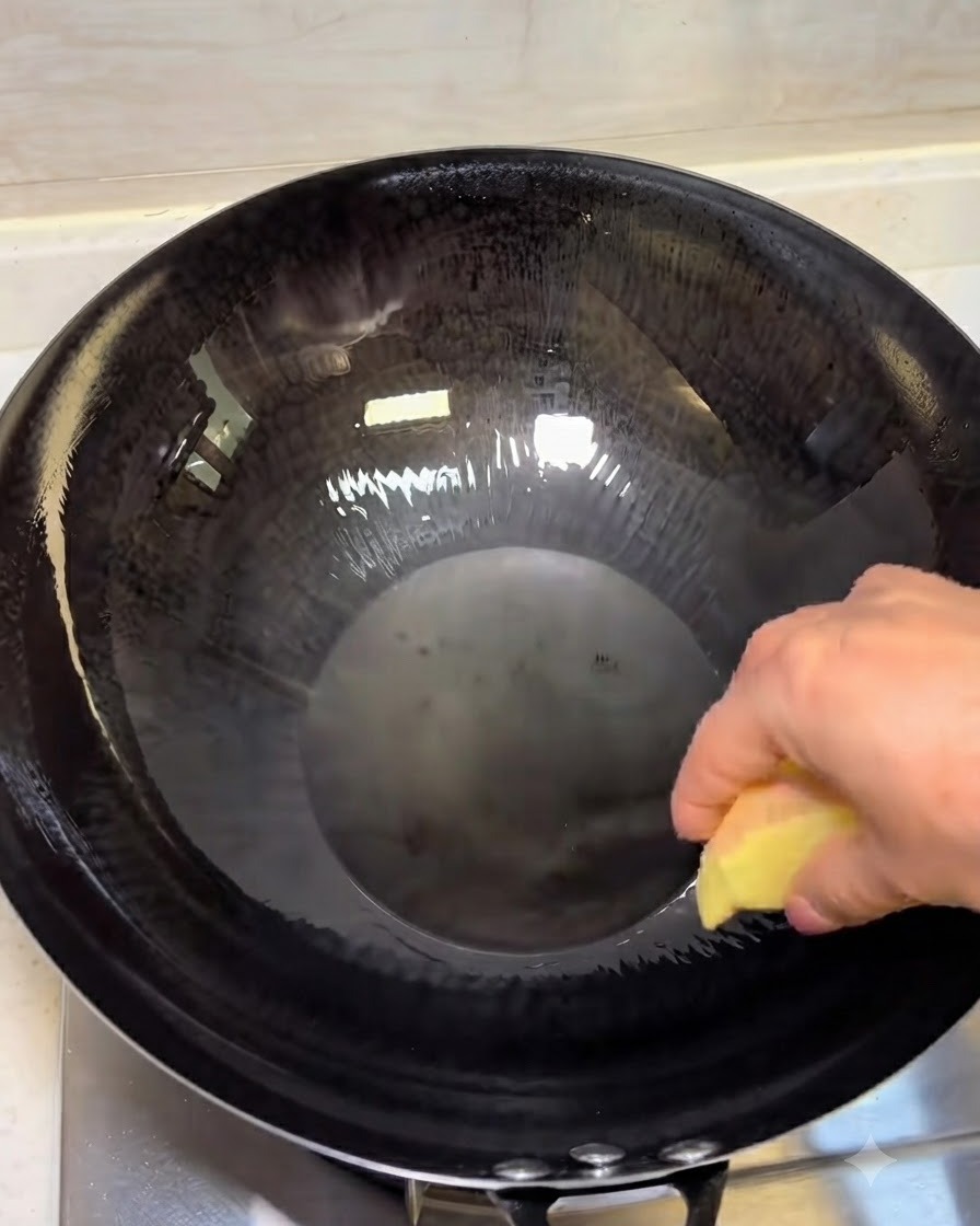 Rodajas de jengibre friéndose en aceite caliente dentro de un wok oscuro.