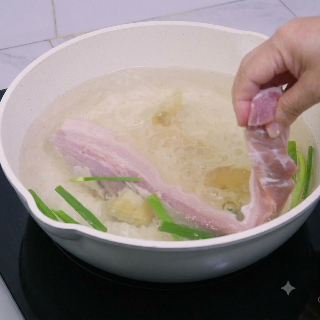 Tiras de panceta de cerdo siendo bajadas a una olla con agua hirviendo.