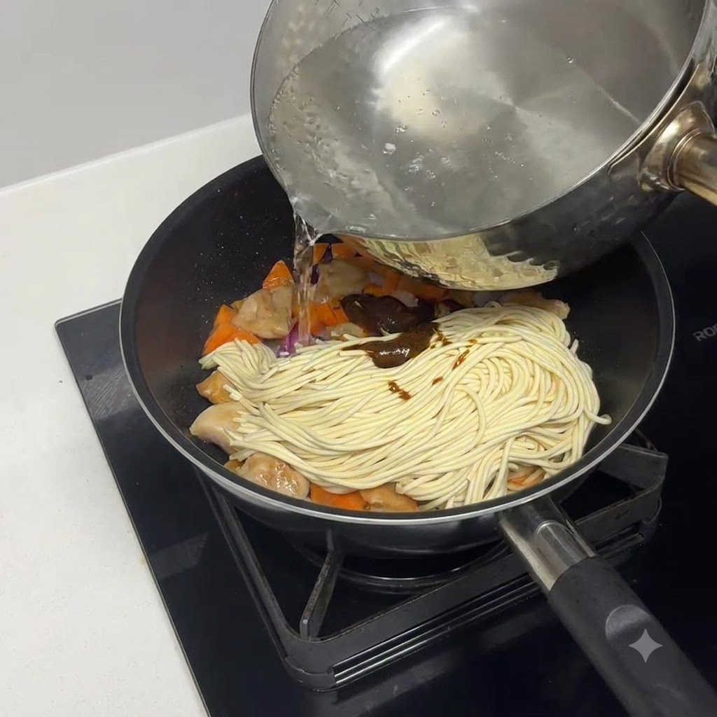 Agua hirviendo siendo vertida en la sartén sobre la pasta y los ingredientes.
