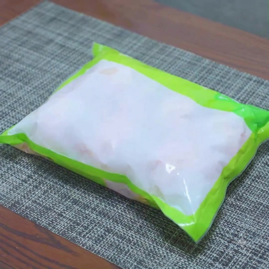 Muslos de pollo congelados en remojo en un bol con agua salada para un descongelamiento rápido.
