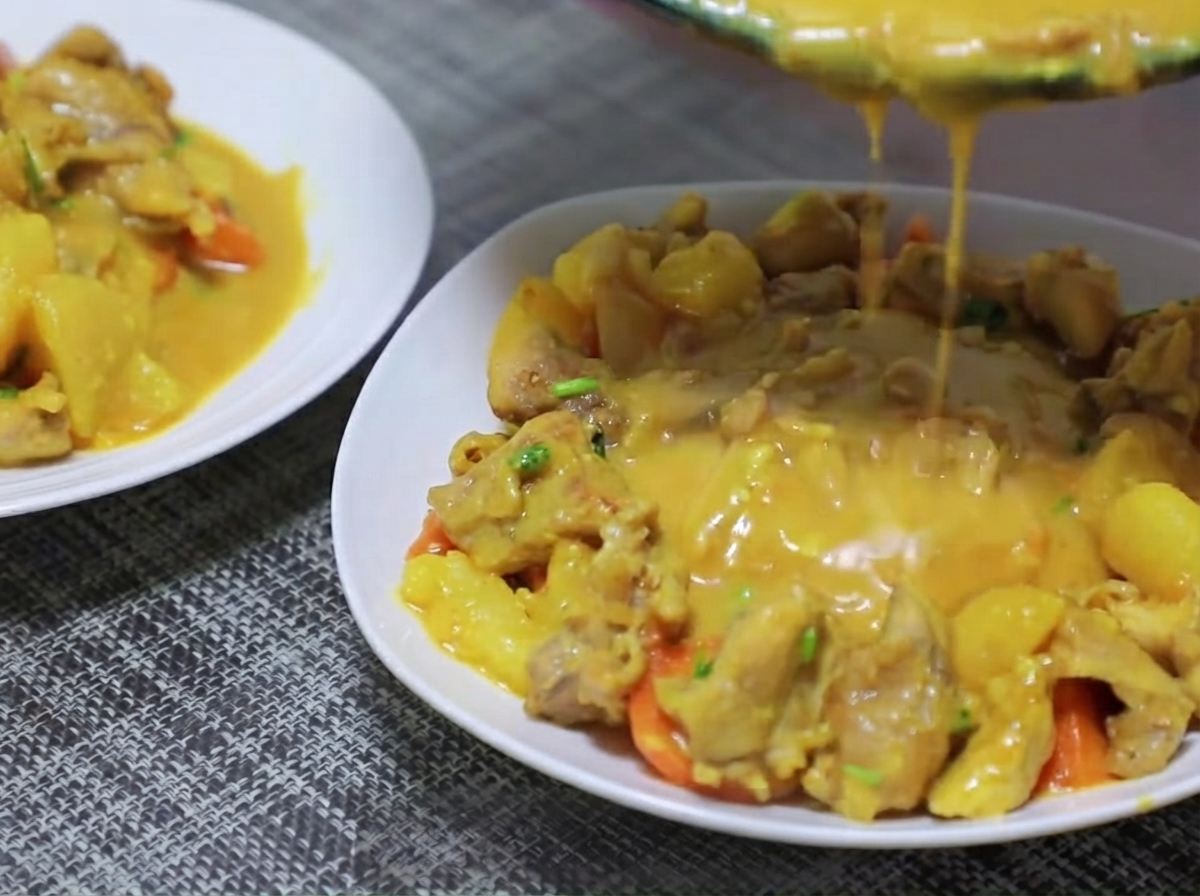 Trozos de papa y zanahoria siendo añadidos a la sartén y sofritos con la base de curry.