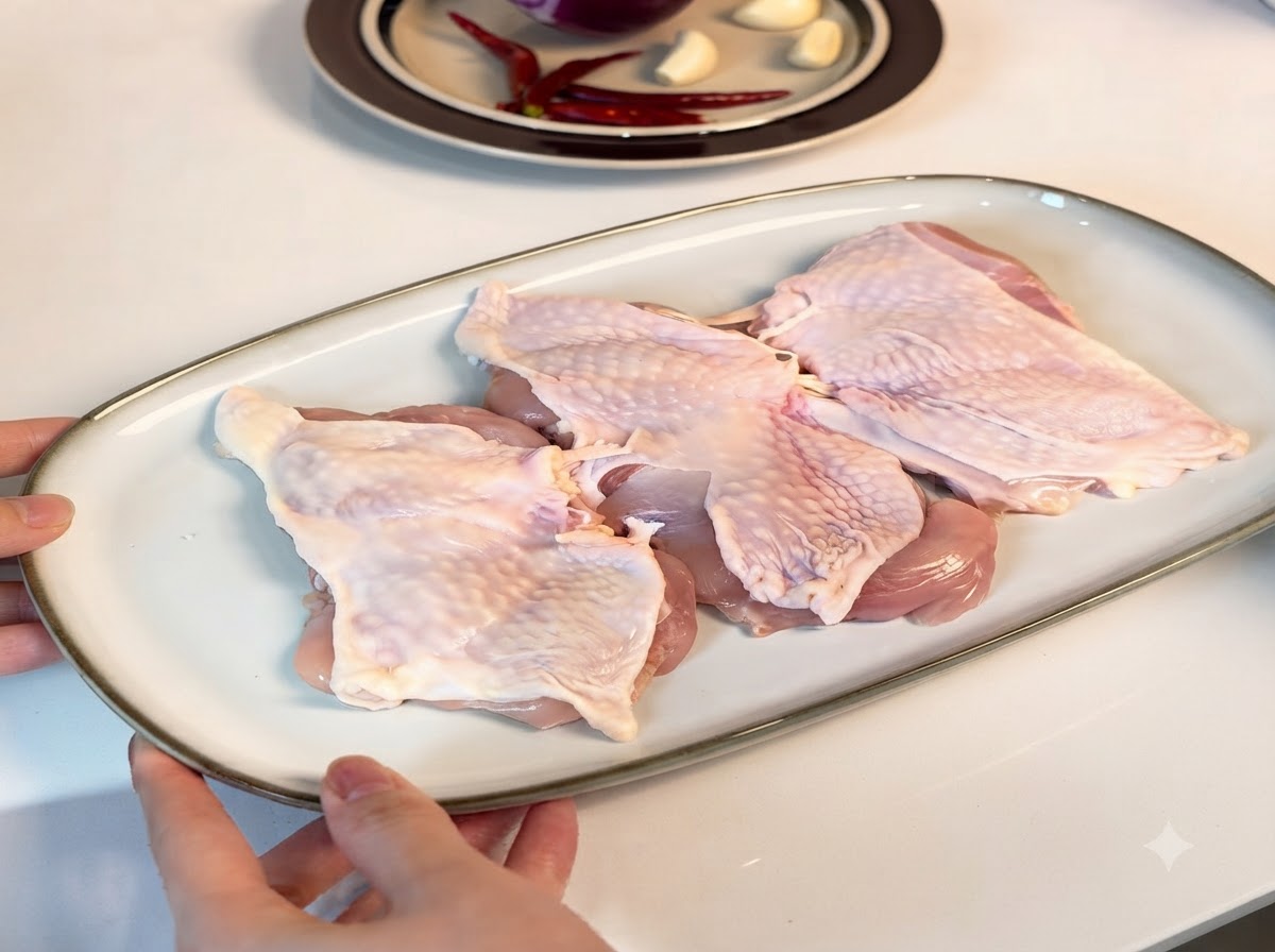 Muslos de pollo deshuesados dispuestos en un plato blanco, cubiertos con condimentos.