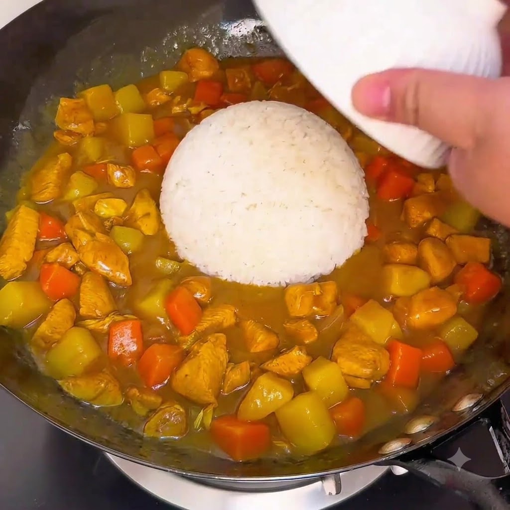 Un bol de arroz blanco siendo invertido en la salsa de curry hirviendo en un wok.