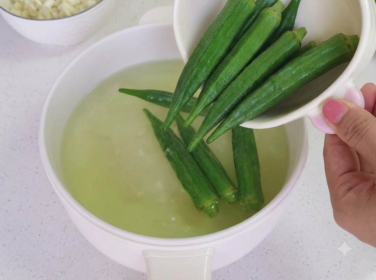 Okra cocida cortada en pequeños segmentos sobre una tabla de cortar de madera.