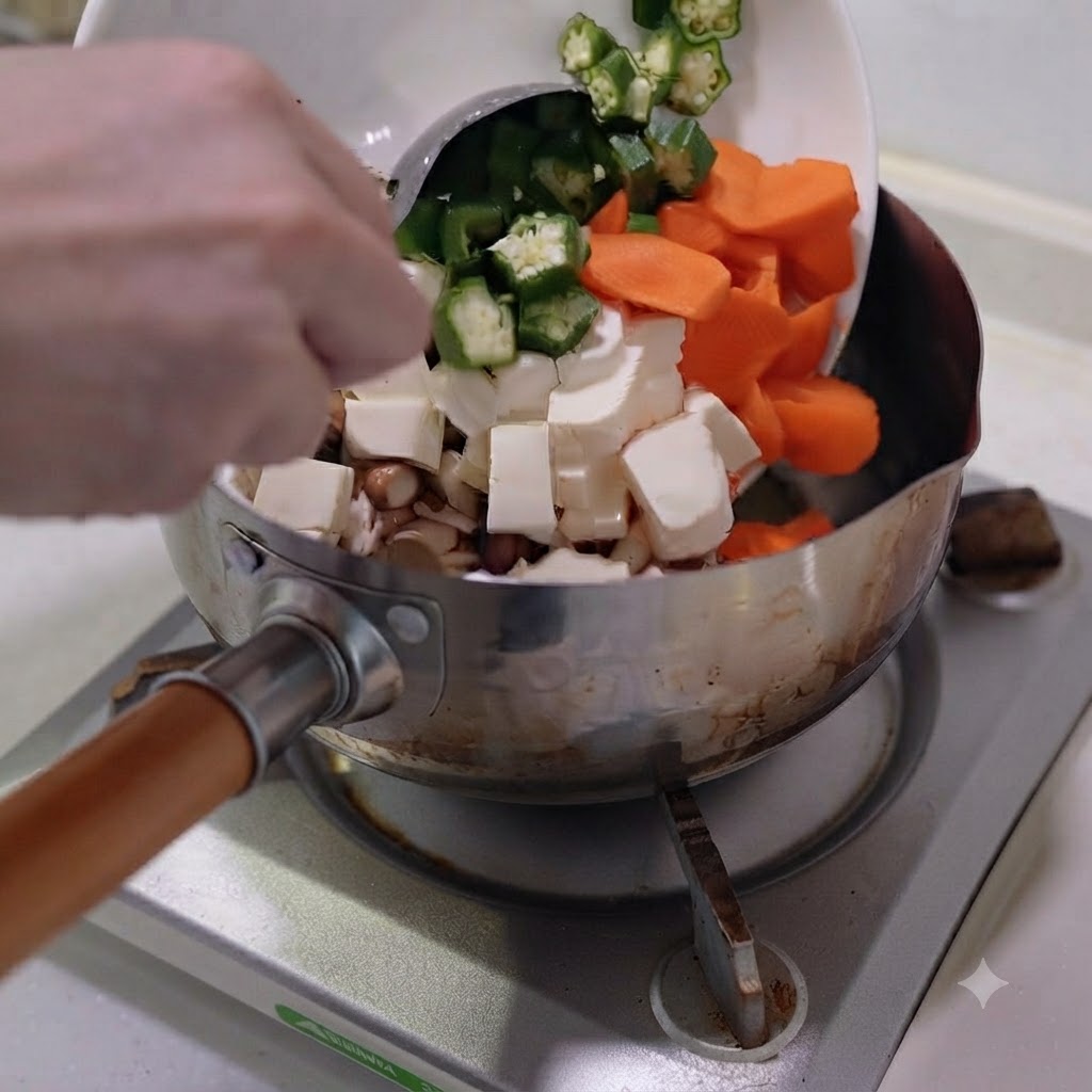 Verduras picadas y tofú vertidos desde un plato blanco a una olla de acero inoxidable.