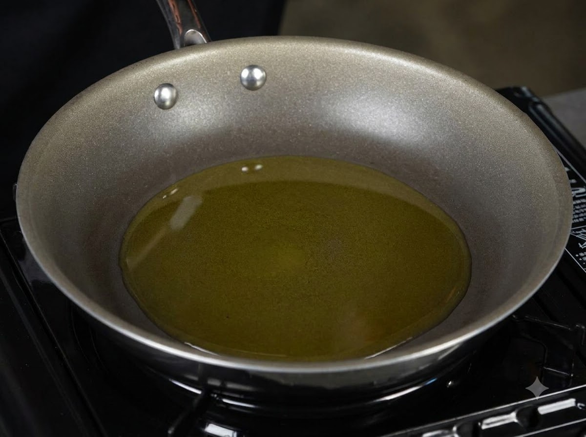 Una sartén llena de aceite de oliva caliente sobre el quemador de una estufa.