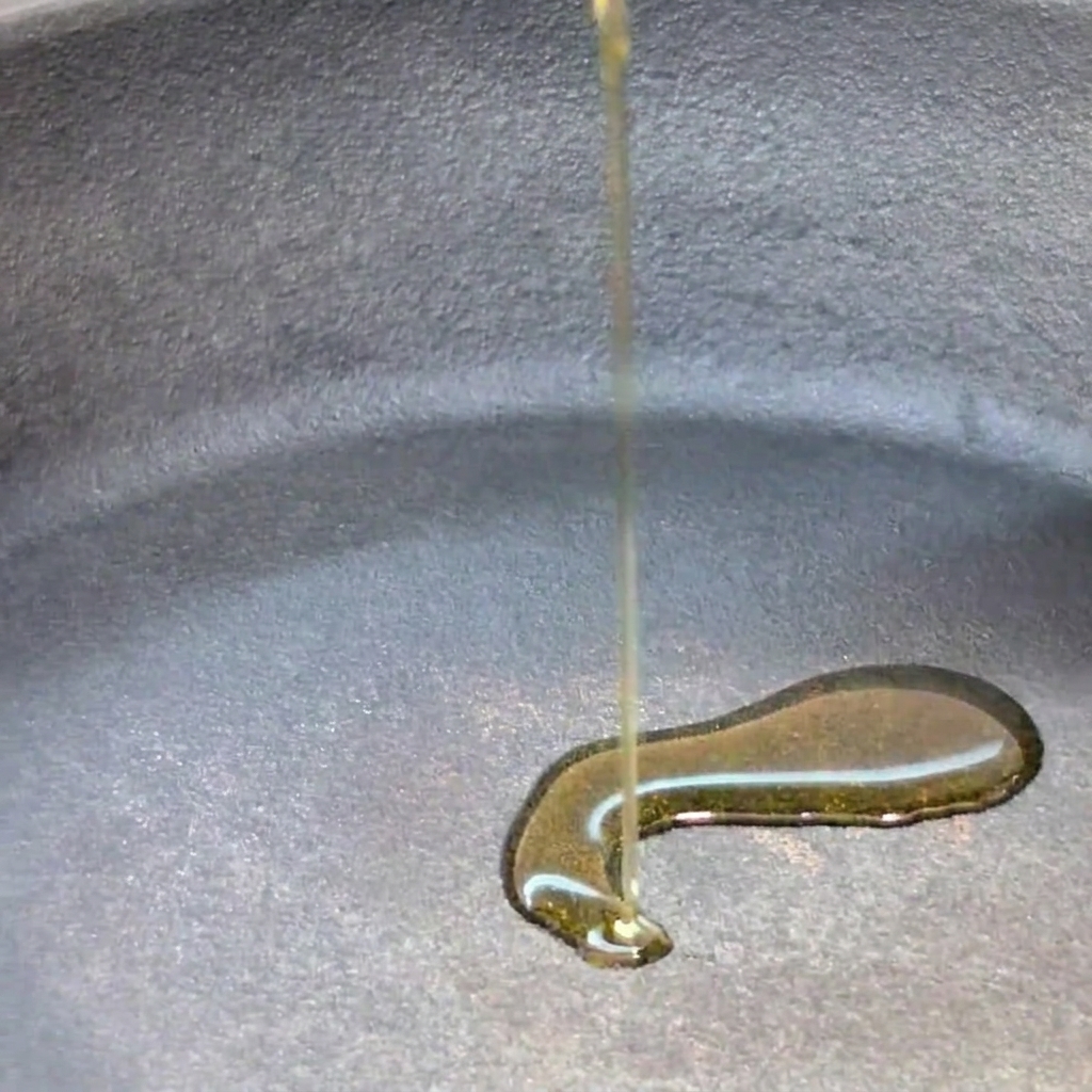 Aceite de oliva virgen extra siendo vertido en una sartén fría.