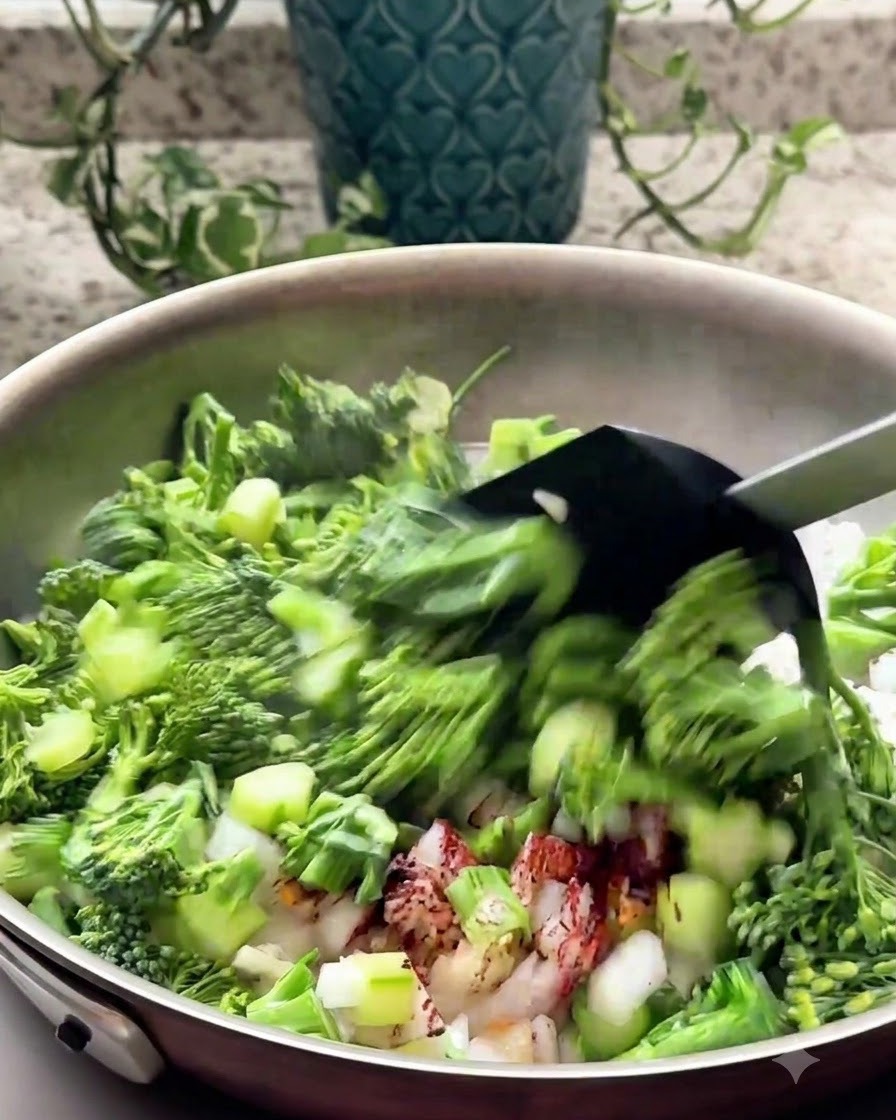 Brócoli picado y aromáticos siendo salteados en una sartén con una espátula negra.