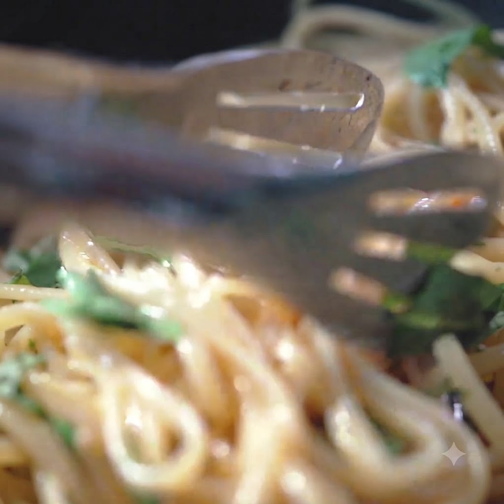Pimienta negra y sal marina siendo espolvoreadas sobre los fideos de pasta en una sartén caliente.