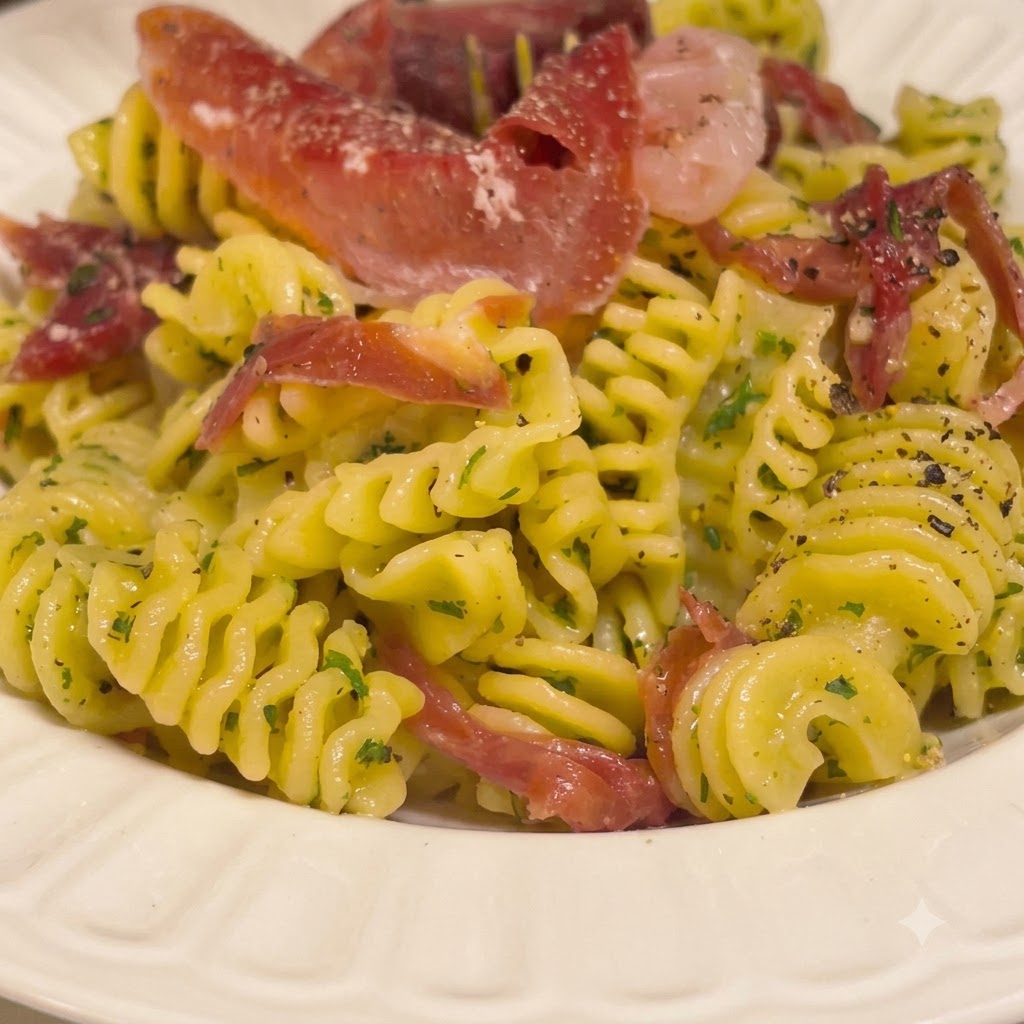Pasta espiral cocida siendo revuelta en un bol blanco con una salsa rica de mantequilla usando pinzas de cocina.
