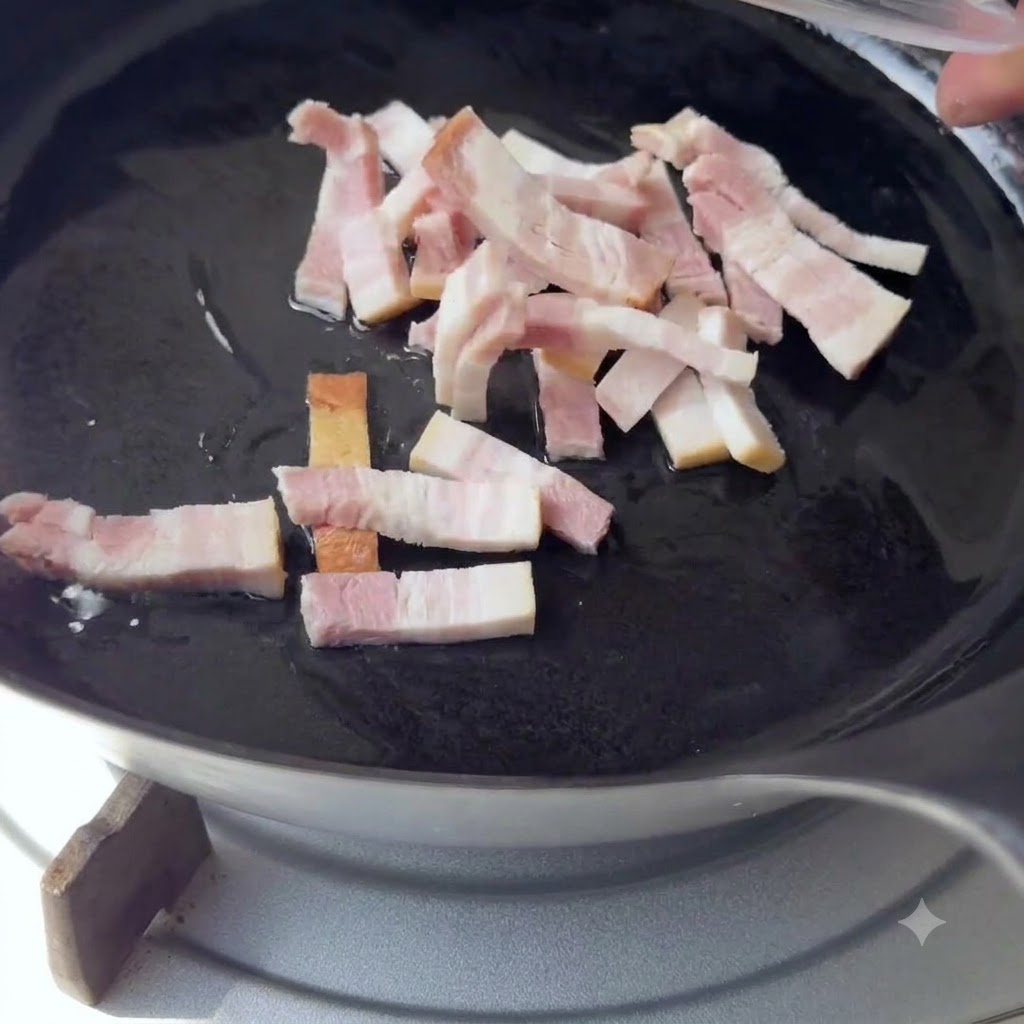 Pequeñas tiras de tocino cayendo en una sartén negra con aceite caliente.