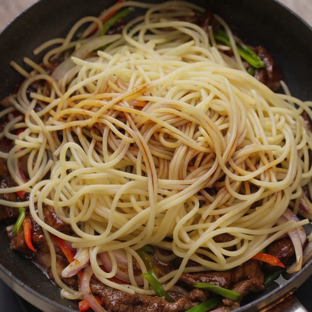 Salsas siendo rociadas sobre fideos espagueti y carne dentro de una sartén de cocina.