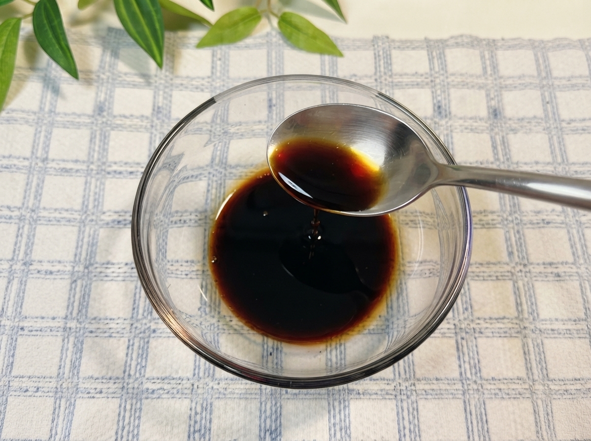 Salsa de soja y otros condimentos mezclándose dentro de un tazón de vidrio con agua.