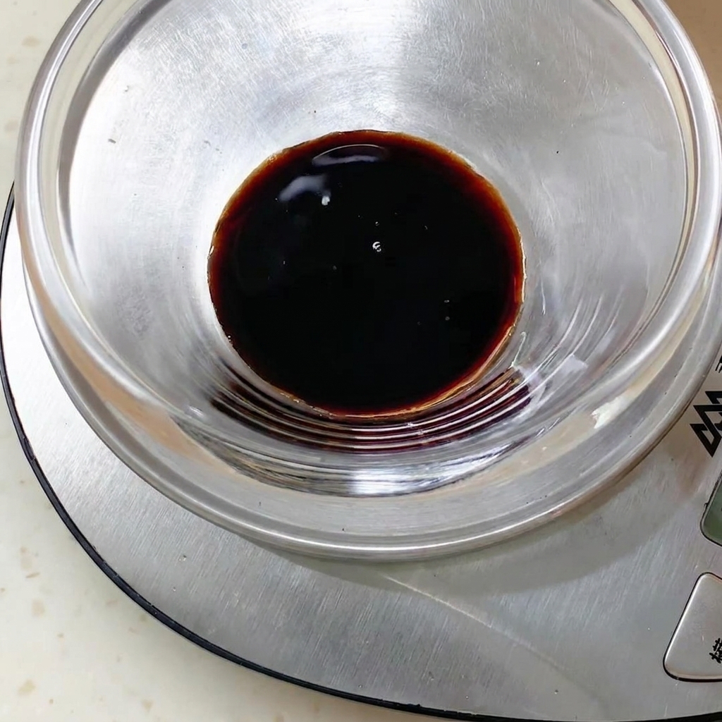 Mezcla de salsa oscura dentro de un bol de vidrio colocado sobre una báscula de cocina digital.