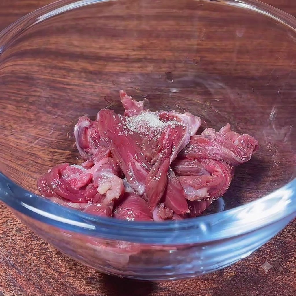 Trozos de ternera cruda en un bol de vidrio con azúcar, listos para mezclar con los ingredientes de la marinada.