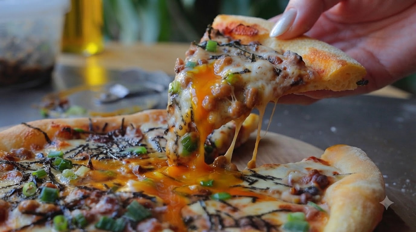 Una porción de pizza recién horneada con natto, mostrando los hilos de queso derretido y una yema de huevo líquida cayendo por los bordes.