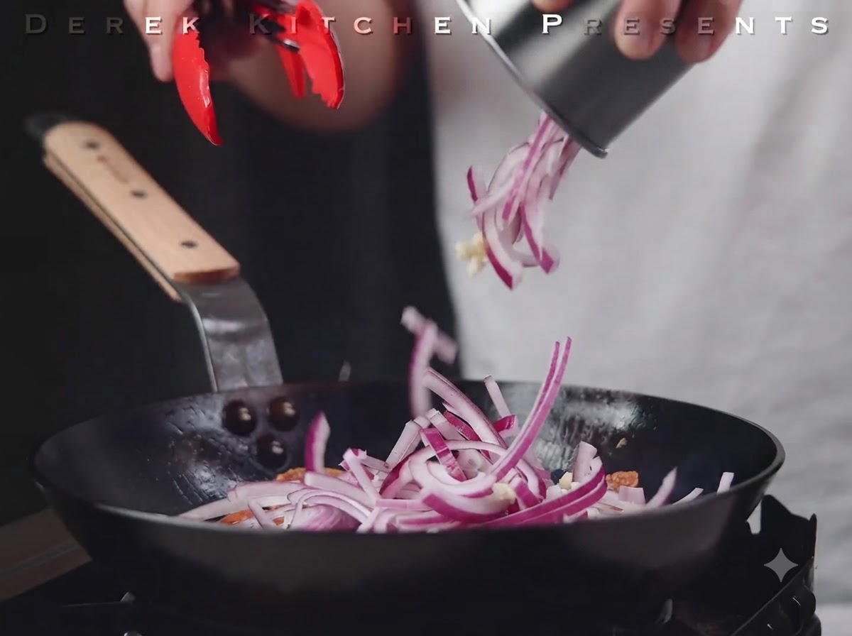 Cebolla roja en rodajas y ajo vertiéndose en la sartén sobre el salami.