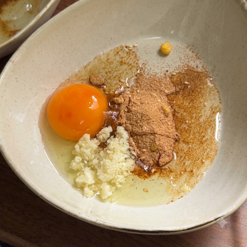 Mayonesa exprimiéndose en un tazón con una yema de huevo cruda, ajo y polvo de condimento.