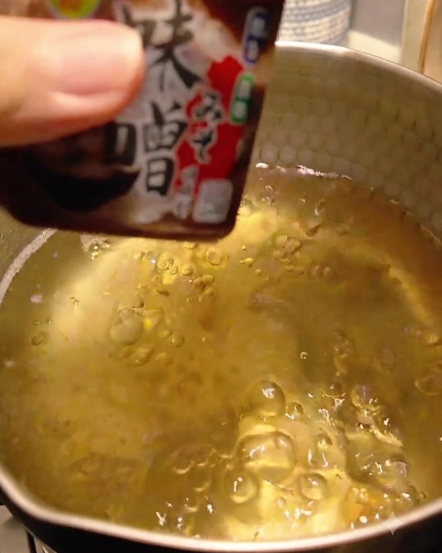 Pasta de miso siendo añadida y disuelta en el caldo dashi.