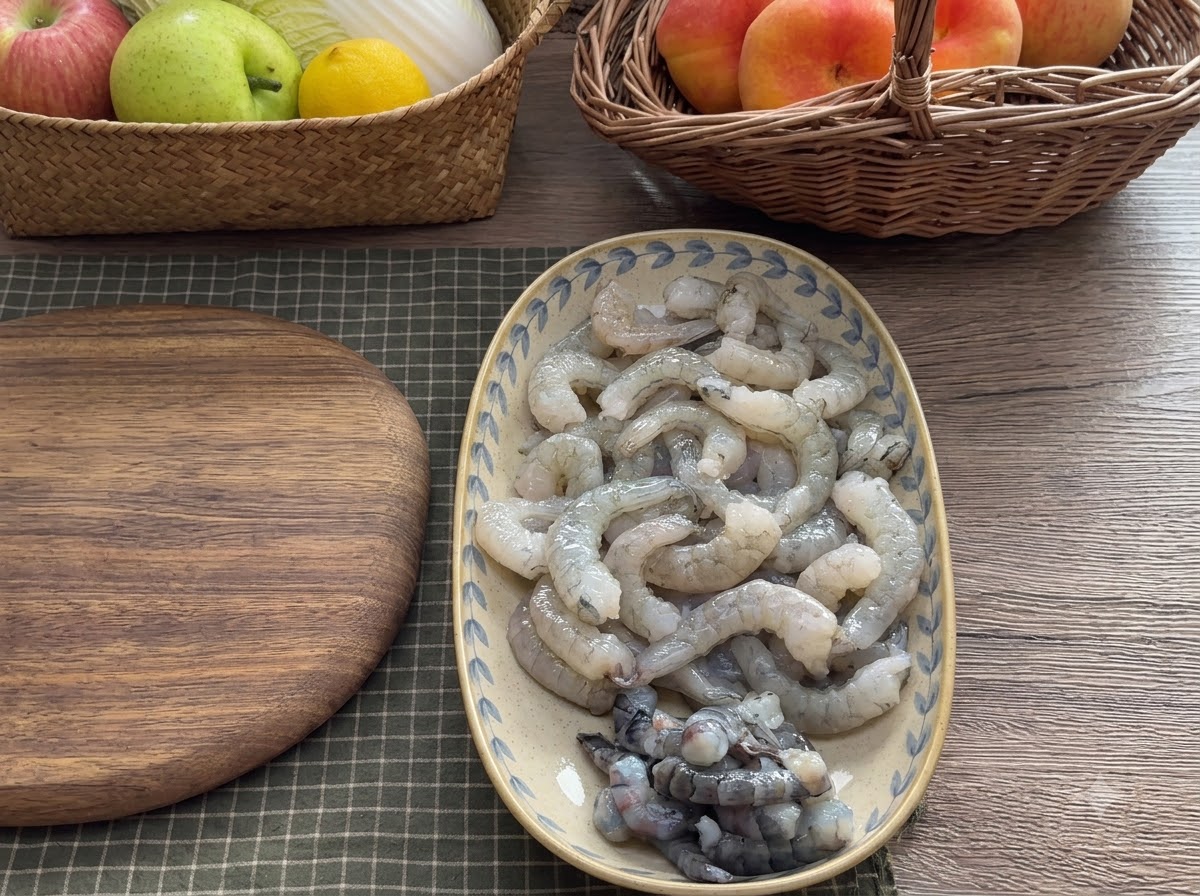Carne de camarón picándose en una tabla de cortar de madera con una cuchilla en diferentes tamaños.