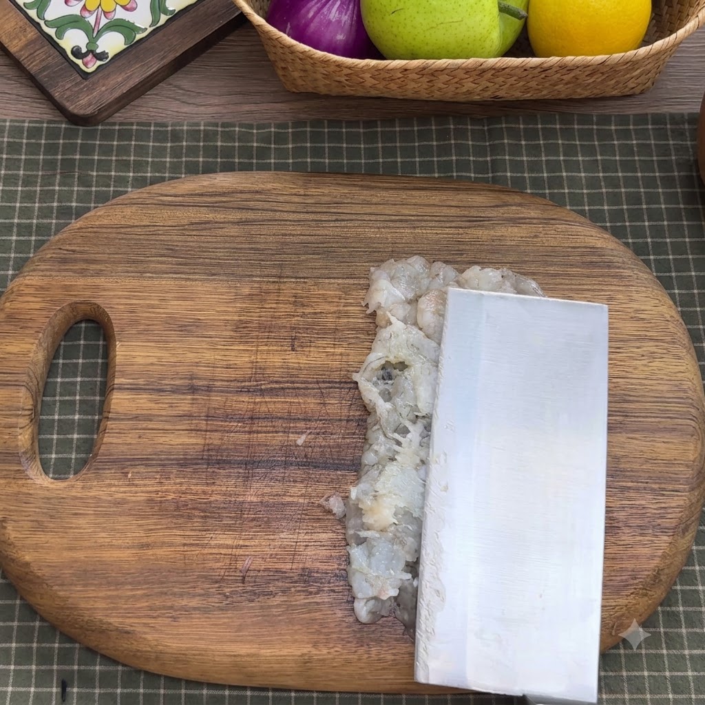 Carne de camarón picada en un bol de mezcla metálico con condimentos, claras de huevo, almidón y agua.