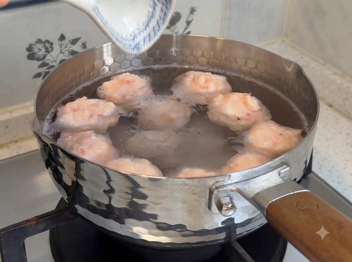 Albóndigas de camarón caseras y rellenas hirviendo a fuego lento en una olla con agua tibia en la estufa.