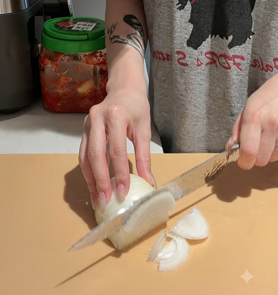Manos cortando cuidadosamente una cebolla blanca en una tabla de cortar usando un cuchillo de chef.