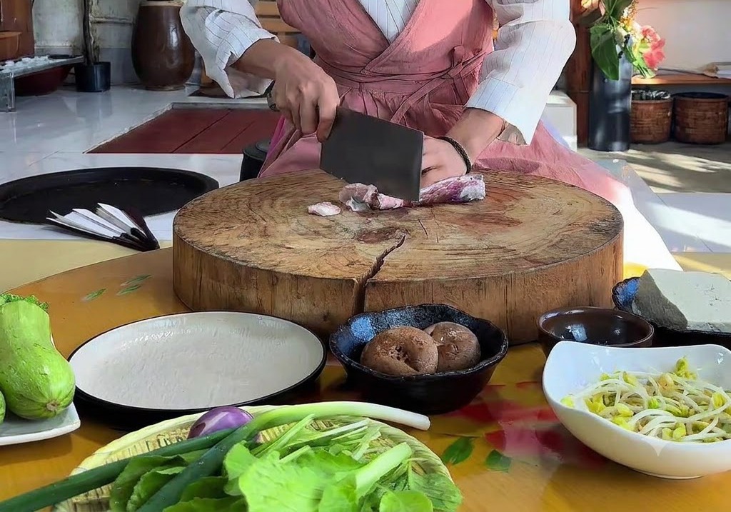 Manos usando un cuchillo de carnicero para cortar panceta de cerdo cruda en una gran tabla de cortar de madera.