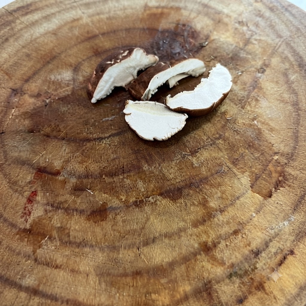 Champiñones shiitake frescos cortados en finas rebanadas sobre una tabla de cortar de madera.