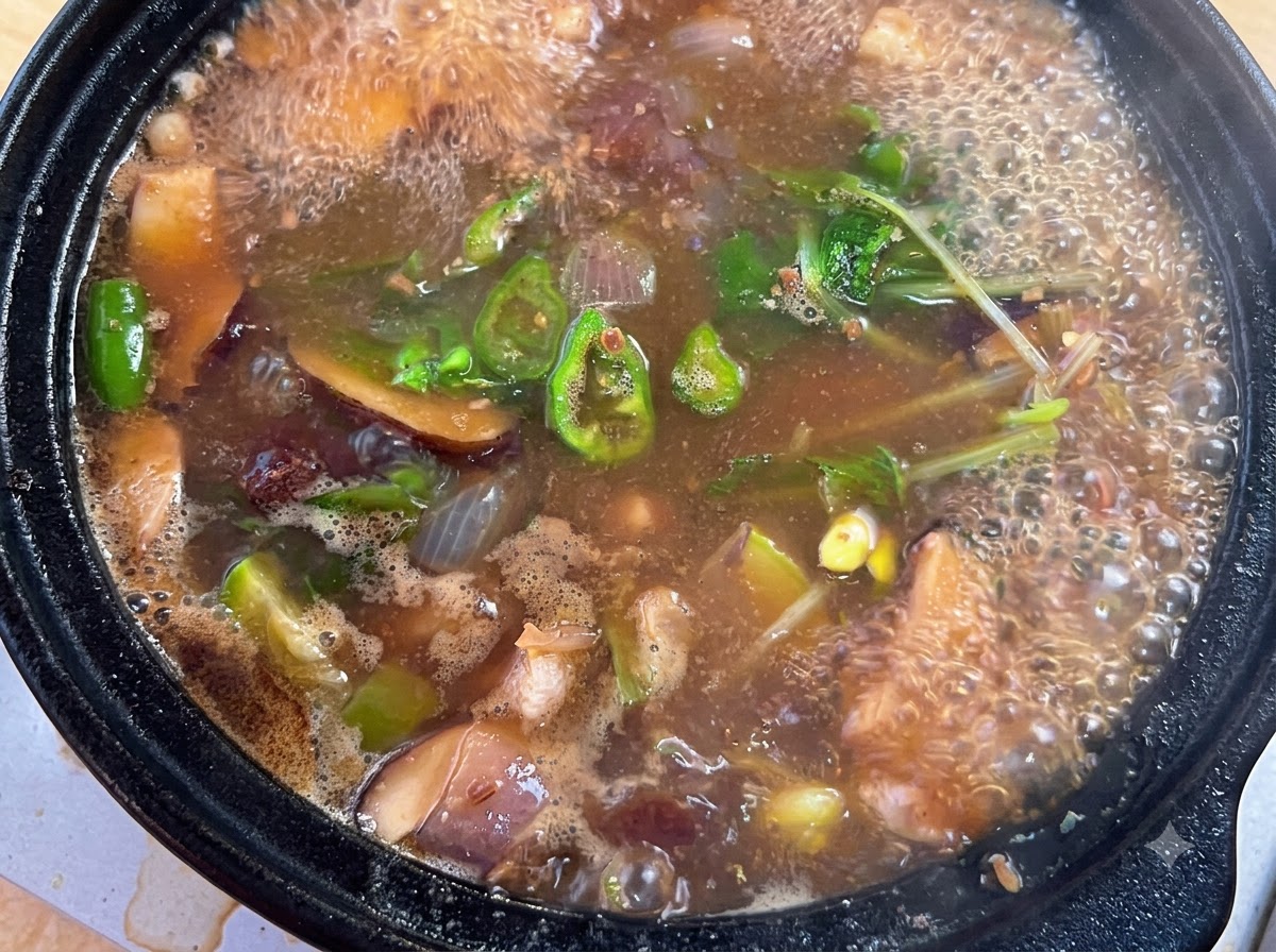 Sazonador de carne en polvo, chile en polvo y cebolletas picadas siendo añadidos a la olla burbujeante del estofado.
