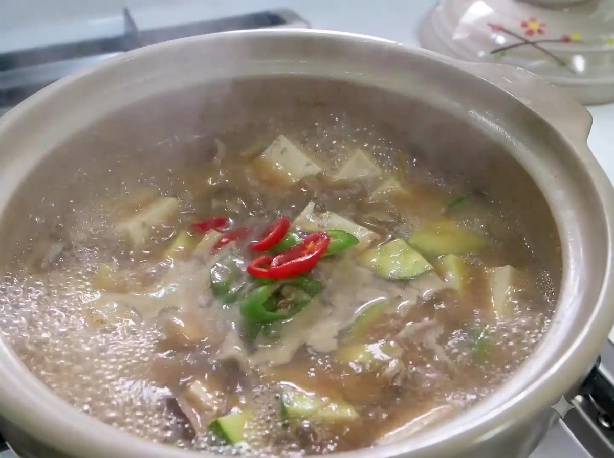 Rodajas de chile rojo y verde y cebolleta a fuego lento en una olla burbujeante de Doenjang Jjigae.