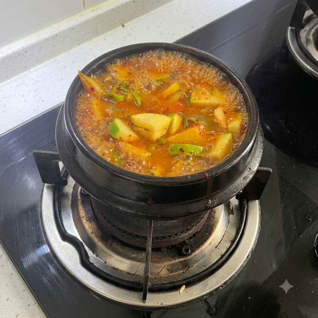 Una olla burbujeante de estofado anaranjado rojizo cocinándose a fuego lento en una hornalla.