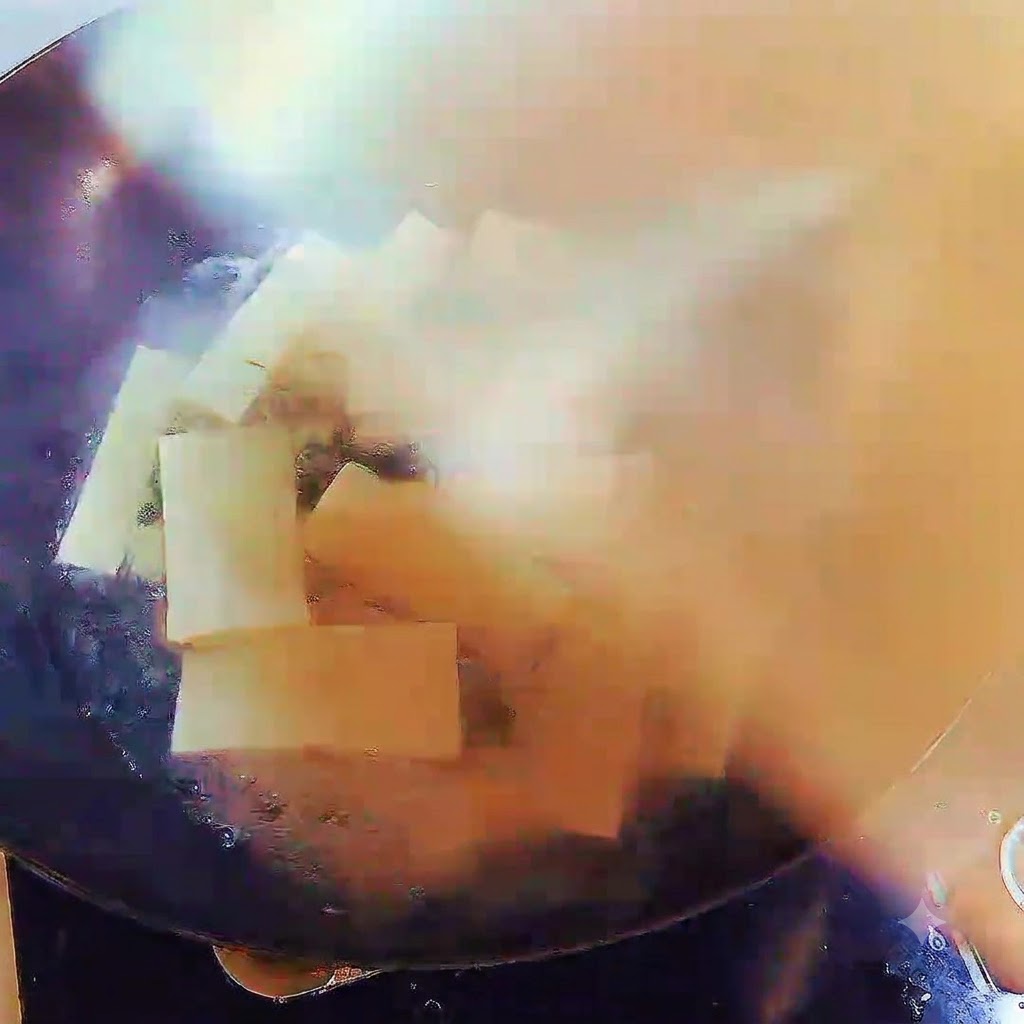 Un wok lleno de sopa hirviendo y tiras de tofu, cubierto de forma segura con una tapa.