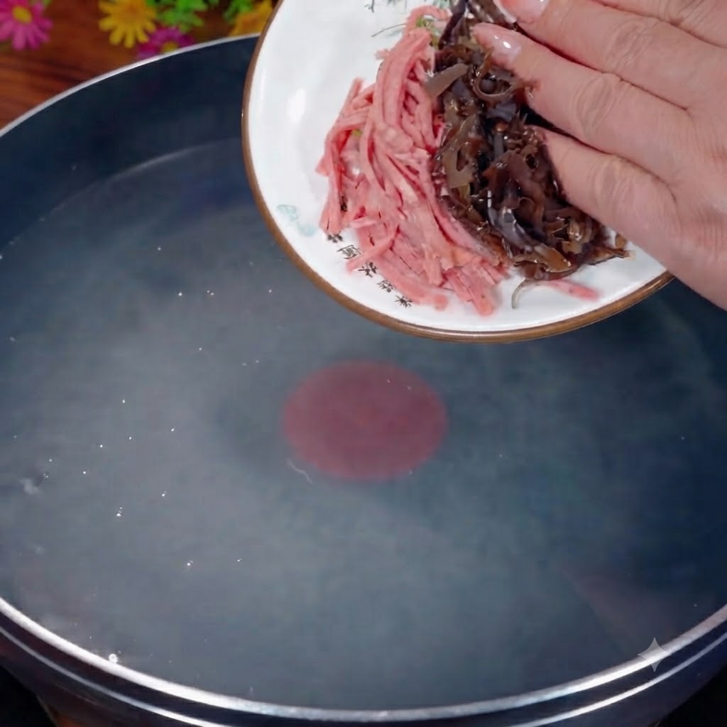 Hongo negro y jamón en tiras siendo vertidos desde un plato blanco a una olla con agua hirviendo.