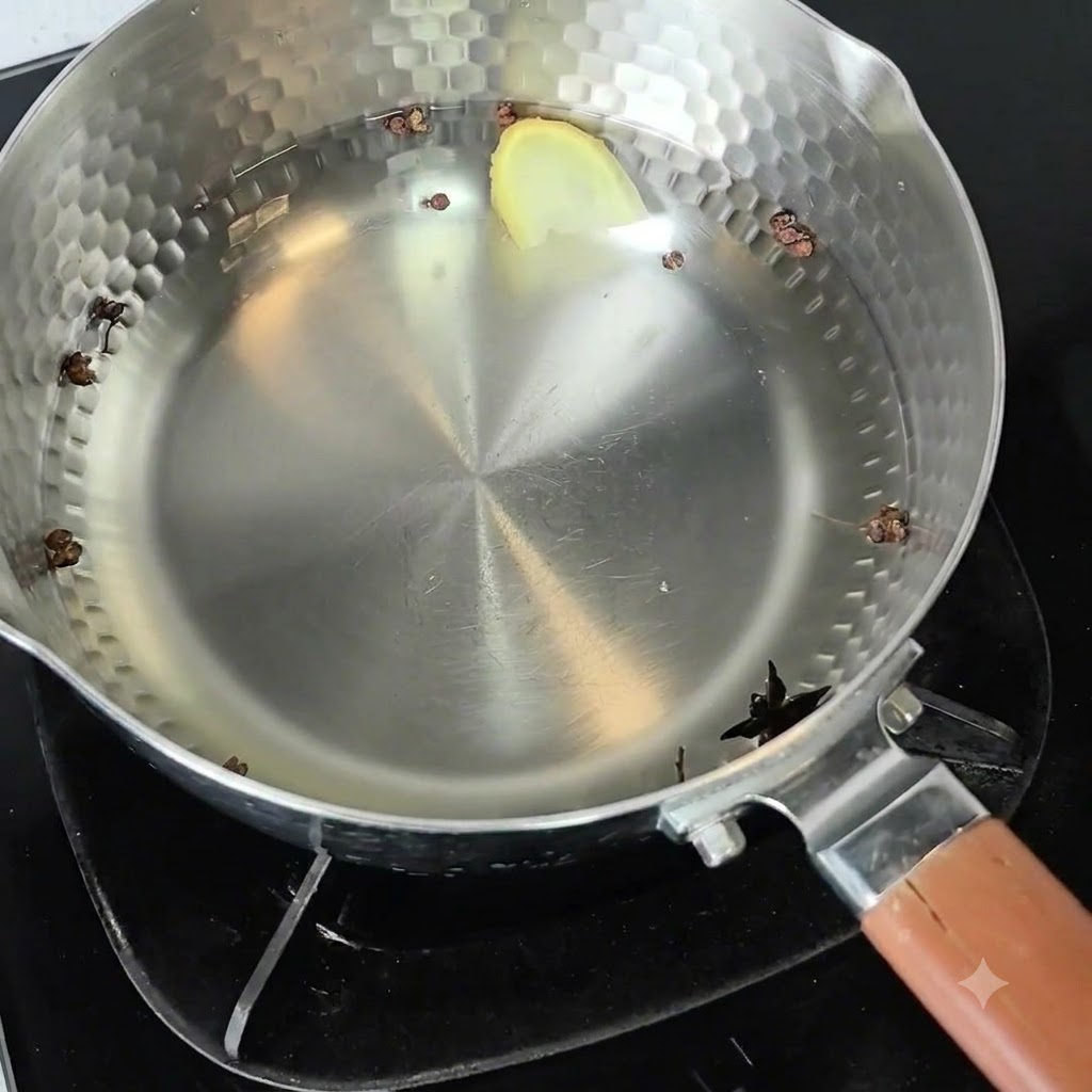 Una olla de metal llena de agua fría, granos de pimienta de Sichuan, anís estrellado y una rodaja de jengibre colocada en un quemador.