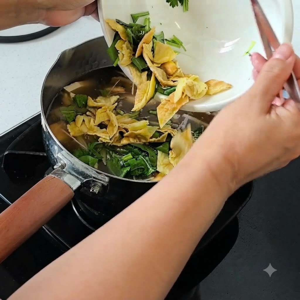 Cebollines picados, cilantro y huevo centenario picado siendo vertidos desde un tazón blanco en una olla de sopa a fuego lento.