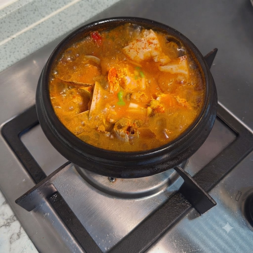 Estofado coreano picante de tofu suave terminado y adornado con cebolleta picada en una olla de piedra caliente.