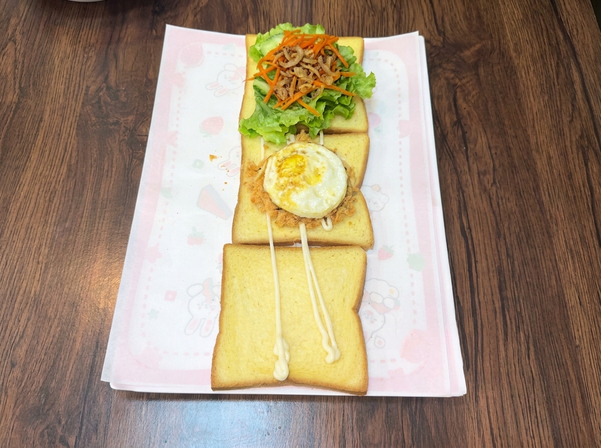Un huevo recién frito colocado encima de una capa de floss de carne sabroso y migas de algas en una rebanada de pan tostado.