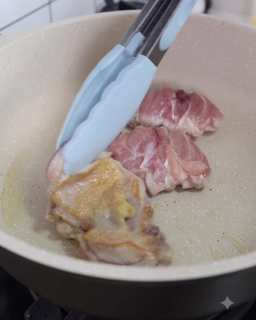 Piezas de pollo siendo volteadas en la sartén usando pinzas de cocina.